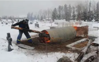  ?? JOANNA SMITH /TORONTO STAR ?? Aaron Janvier adds to the fire that will thaw the ground so that a grave can be dug in La Loche, Sask.