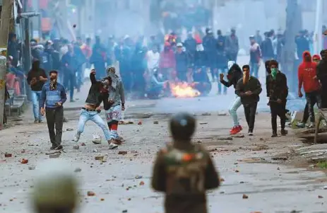  ?? AP ?? Protesters throw stones on government forces in Srinagar on Monday. A tourist died after crowds targeted several vehicles during protests called against the deaths on Sunday of five militants and six civilians.