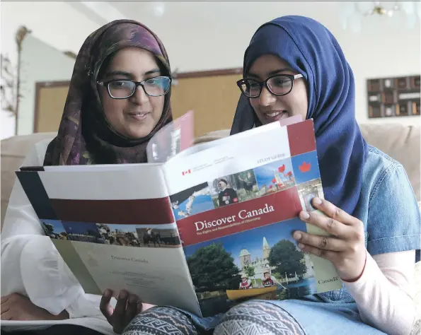  ?? MICHELLE BERG ?? Samia Sami, left, flips through the Discover Canada study guide with her sister Sania Sami, who placed second in the Regina Leader-Post/Saskatoon StarPhoeni­x Canada 150 essay contest. Sania wrote in her essay how she used the book to help her mother...