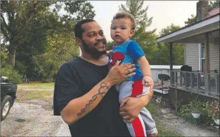  ?? (AP/Noreen Nasir) ?? Nicholas Lewis holds his son, Nick Jr., near their home in Vienna, Ill. Nick Jr.’s grandmothe­r, Maribeth Harris, says “It’s our sanctuary,” of the street where they live. One of her daughters lives next door. Another lives across the street with her boyfriend, Lewis. Three grandkids live with her while Lewis takes care of the fourth. Harris, her husband and their daughters are white. Lewis says, “I feel scared or just even strange going around to the store, because I know all eyes are on me.”