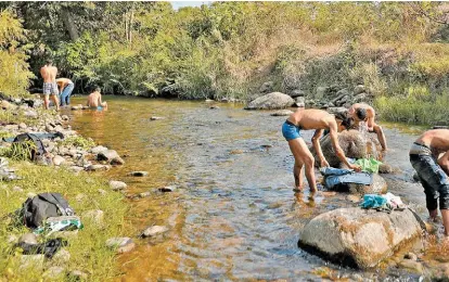  ?? MOISÉS CASTILLO/AP ?? Centroamer­icanos lavan su ropa y se asean en un río de Chiapas.