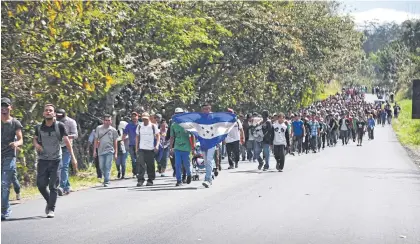  ??  ?? Honduran migrants carry their national flag as they walk through Guatemala on Thursday after crossing the border on their way to the US.