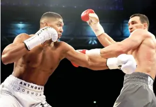  ??  ?? Anthony Joshua (L) and Wladimir Klitschko trade punches during the WBA and IBF championsh­ip fight at Wembley Stadium on Saturday night
