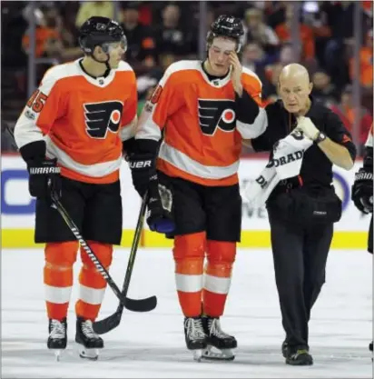  ?? TOM MIHALEK — THE ASSOCIATED PRESS ?? Flyers forward Nolan Patrick, center, being helped off the ice in a game against Anaheim Oct. 24, hasn’t played since then due to an “upper-body injury.” But general manager Ron Hextall said Thursday that the rookie’s ailment is progressin­g nicely.