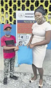  ?? (Photo: Rosalee Wood) ?? Grade 3 teacher Melecia Samuels (right) presents a care package to a Georges Plain Primary student recently.