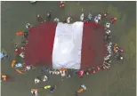  ?? GUADALUPE PARDO / AP PHOTO FILES ?? Swimmers, paddlers and surfers form a circle around a Peruvian national flag as a show for unity and peace.