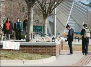  ?? ?? Michigan State students heading back to classes Monday stop at a memorial at Berkey Hall dedicated to the three students killed in the mass shooting on Feb. 13.