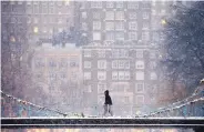  ?? MICHAEL DWYER/ASSOCIATED PRESS ?? A walker crosses the pedestrian bridge in the Public Garden during a snowstorm in Boston on Saturday. Southern New England had over a foot of snow.