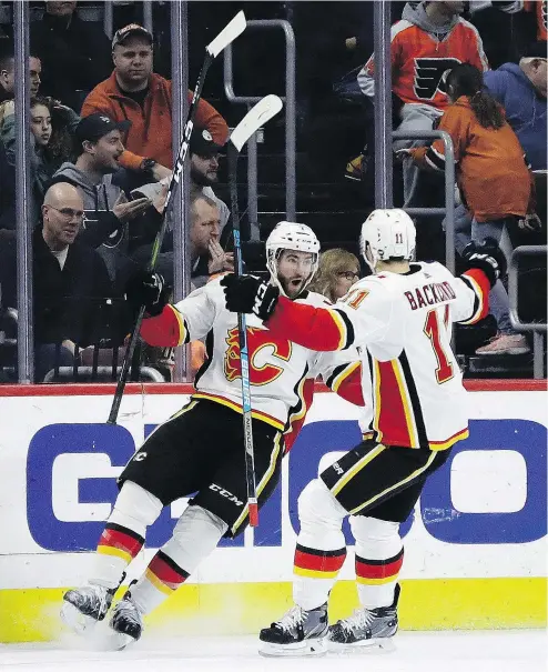  ?? — THE ASSOCIATED PRESS ?? Calgary’s TJ Brodie, left, celebrates with teammate Mikael Backlund after Brodie scored the game-winning goal in overtime against the Flyers at Wells Fargo Center in Philadelph­ia on Saturday.