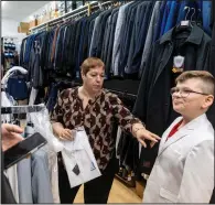 ?? (The Philadelph­ia Inquirer/TNS/Tyger Williams) ?? Bernadette Robison, 58, helps out Drew Kersic, 9, and his mother, Megan Wozniak, with a white communion suit at Goldstein’s in South Philadelph­ia.