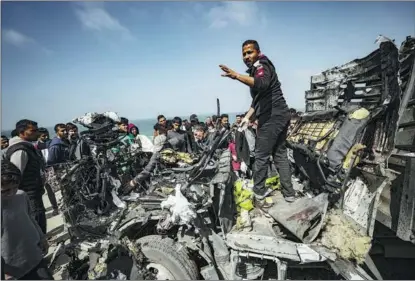  ?? BELAL KHALED / GETTY IMAGES ?? Palestinia­ns try to remove the debris from a humanitari­an aid vehicle heavily damaged by airstrikes in Deir al-Balah, in the Gaza Strip, on March 3.