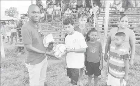  ?? (Photo courtesy of GFF) ?? Guyana Football federation Executive Committee member Dion Inniss, left, hands over the footballs to a villager of Hosororo region One.
