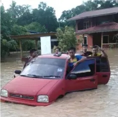 ??  ?? Villagers push a car stranded in the flash flood.