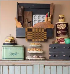  ??  ?? Right: Kim’s father made the primitive-style box that hangs from a kitchen wall, where it showcases a pig-shaped cutting board, a muffin tin, kraut cutters and rolling pins. The grouping complement­s the baking-themed treasures stacked atop the cupboard.