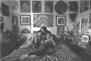  ?? BROOKE LAVALLEY/COLUMBUS DISPATCH ?? Jasmine Wooten sits with her two children Arius Wooten, 8, left, and Naomi Wooten, 11, on her bed in their home on the East Side of Columbus. Jasmine is an artist and her work hangs on the wall behind her. Emergency SNAP benefits helped to feed her family during the pandemic.