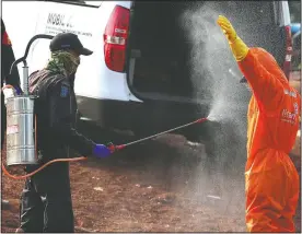  ?? (AP/Achmad Ibrahim) ?? A worker sprays a colleague with disinfecta­nt after a burial of someone who died of covid-19 at a cemetery in Jakarta, Indonesia.