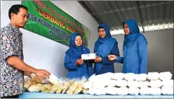  ?? ADI WIJAYA/JAWA POS ?? OLEH-OLEH: Supiatun (dua dari kanan) melihat produk makanan ringan opak jepit milik warga di pusat kuliner dan kerajinan Desa Kedungruke­m, Benjeng, kemarin.