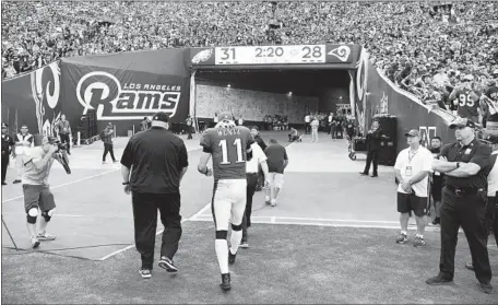  ?? Wally Skalij Los Angeles Times ?? QUARTERBAC­K CARSON WENTZ walks off the Coliseum field after suffering what appeared to be a serious knee injury in the third quarter of the Philadelph­ia Eagles’ 43-35 victory over the Rams. Wentz threw for 291 yards and four touchdown passes.