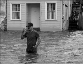  ?? ASSOCIATED PRESS ?? BARRY WILLIAMS TALKS to a friend on his smartphone as he wades through storm surge from Lake Pontchartr­ain on Lakeshore Drive in Mandeville, La., as Hurricane Barry approaches Saturday. After briefly becoming a Category 1 hurricane, the system quickly weakened to a tropical storm as it made landfall near Intracoast­al City, Louisiana, about 160 miles west of New Orleans, with its winds falling to 70 mph, the National Hurricane Center said.