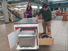  ?? JORDANA JOY — THE MORNING JOURNAL ?? Jennifer Black, director of marketing at Lorain Public Library System, left, and Sam Lewis, strategic initiative­s manager, roll out the new Charlie Cart, a mobile kitchen to be used for the library’s culinary education programs. One cart will be available at Domonkas Branch and another at the South Lorain Branch.