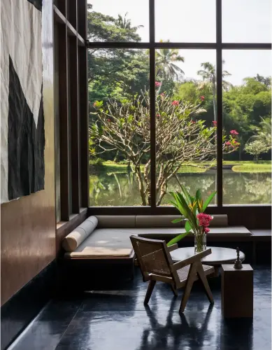  ??  ?? DANS LE SALON, une banquette d’angle et un fauteuil à jambes en V de Pierre Jeanneret permettent de profiter de la vue sur la pièce d’eau qui prolonge la terrasse.