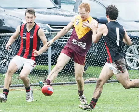  ??  ?? Drouin’s David Miller scrambles a defensive kick early in the senior clash against Maffra at Drouin on Saturday as opponents Mitch Bennet and Dylan Alexander (1) close in.