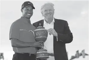  ?? AP ?? In 2013, Tiger Woods stood with Donald Trump holding the Gene Sarazen Cup for winning the Cadillac Championsh­ip in Doral, Florida.