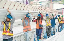  ?? DITA ALANGKARA/AP ?? Workers carry material during the constructi­on of Jakarta Internatio­nal Stadium in 2021 in Indonesia. Asia-Pacific economies are forecast to slow sharply this year.