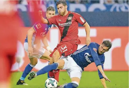  ?? FOTO: AP ?? Zweikampf im Regen: Leverkusen­s Kevin Volland (rotes Trikot) balgt sich mit Schalkes Leon Goretzka um den Ball. Matija Nastasic (hinten) schaut zu.