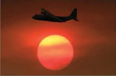  ?? MIKE ELIASON — SANTA BARBARA COUNTY FIRE DEPARTMENT VIA AP ?? In this photo provided by the Santa Barbara County Fire Department, with smoke obscuring the sun in the distance, a Coulson C-130 Air Tanker turns in to make a drop on a hillside near Toro Canyon Road in Carpinteri­a Monday.