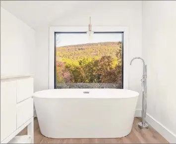  ??  ?? Alon Koppel Photograph­y / Lillie K. Team @ Select Sotheby's Internatio­nal Realty and Alon Koppel Photograph­y When Wallach was designing the High Falls house as an Airbnb rental, she envisioned the view from the bathroom being her main selling point. She installed a picture window and a soaking tub from which to enjoy the Mohonk Preserve views. "I was like, 'This is the money shot of the tub and the mountains...who wouldn't want to sit in this tub and look at this view?'" Not only does Wallach plan to do her "turnkey treatment" to another Hudson Valley home, she's already purchased her next remodeling project: 1777 Quaker Meeting House in Old Chatham, at right. She's aiming to be finished by mid-summer.