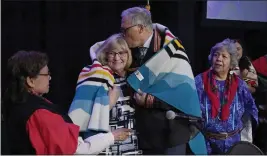  ?? TED S. WARREN — THE ASSOCIATED PRESS ?? Washington Gov. Jay Inslee, second from right, kisses his wife, Trudi, after they were presented a blanket on Thursday in Quil Ceda Village, near Marysville, Wash., in a ceremony after Inslee signed a bill that creates a first-in-the-nation statewide alert system for missing Indigenous people.