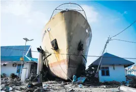  ?? Picture: Jewel Samad/AFP ?? HIGH AND DRY. Quake survivors make their way past a washed out passenger ferry in Wani, Indonesia, after an earthquake and tsunami hit the area on September 28.