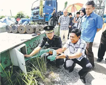  ??  ?? Hafidz (left) checking one of the electrical meters used for the vehicle weighing scales at one of the premises at Batu Kitang yesterday. — Photo by Muhammad Rais Sanusi