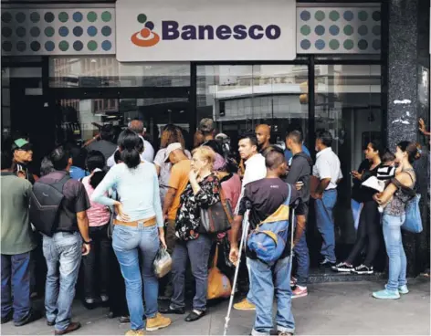  ??  ?? ► Usuarios esperan la apertura de una sucursal del banco Banesco tras un apagón ayer, en Caracas.