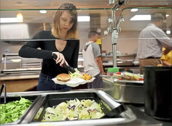  ?? Pam Panchak/Post-Gazette ?? Abbiegail Pistorius, a 10th-grader at Deer Lakes High School, takes food from a salad bar at the school's cafeteria on Friday, May 10, in Cheswick.