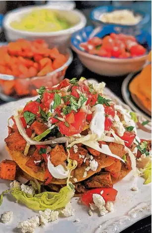  ?? GRETCHEN MCKAY/PITTSBURGH POST-GAZETTE ?? Vegetarian tostadas are stacked with two layers of smashed pinto beans, lettuce, pico de gallo and roasted sweet potatoes and bell peppers. Crumbled queso fresco and lime crema add the crowning touch.