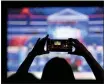  ?? DAVID GOLDMAN — THE ASSOCIATED PRESS
FILE ?? A woman takes a photo of the television while watching a Democratic presidenti­al debate at a watch party in Atlanta.