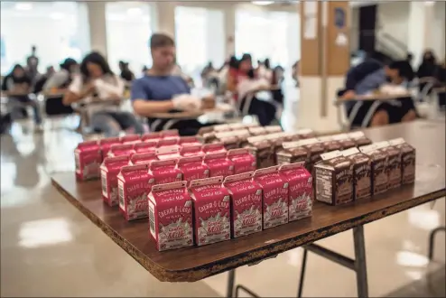  ?? John Moore / Getty Images ?? Students sit for lunch in the cafeteria during the first day of school at Stamford High School on Sept. 8. To ensure social distancing, school administra­tors removed lunch tables and replaced them with individual desks.