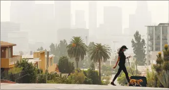  ?? Los Angeles Times/tns ?? Breya Hodge walks her dog, Sophie, as smoke from the Bobcat fire shrouds downtown Los Angeles on Sept. 14.