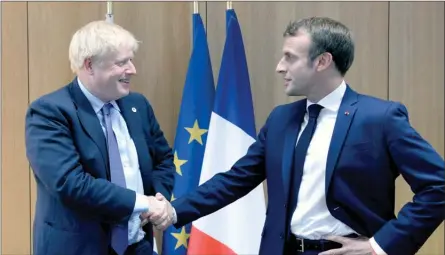  ?? The Canadian Press ?? Britain’s Prime Minister Boris Johnson poses while shaking hands with French President Emmanuel Macron, right, during a European Union leaders summit in Brussels, Belgium, Thursday. Britain and the European Union reached a new tentative Brexit deal on Thursday, hoping to finally escape the acrimony, divisions and frustratio­n of their three-year negotiatio­n.