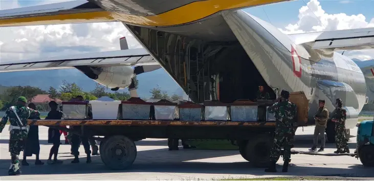  ??  ?? Indonesian military officers load coffins into a carrier aircraft in Wamena, Papua province.