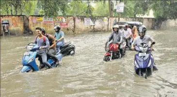  ?? NITIN KANOTRA/HT ?? People struggle their way through kneedeep water on a road after heavy rain in Jammu on Monday.