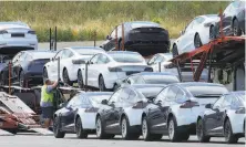  ?? Ben Margot / Associated Press ?? Teslas are loaded onto carriers at the Fremont plant in May. The company plans to develop a less expensive model.