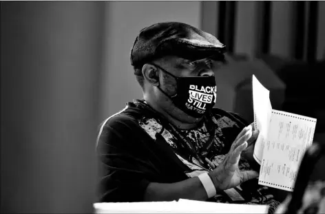  ?? AP Photo/Brynn Anderson ?? In this Nov. 4 file photo, an election worker holds a ballot as vote counting in the general election continues at State Farm Arena in Atlanta.