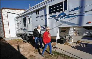  ?? RICK BOWMER / AP ?? Kathy and Bud Scottwalk past their fifth wheel travel trailer inWest Valley, Utah. Many snowbirds who live part-time inwarmer climates to escape coldweathe­rwon’t be flocking south thiswinter. While their absence is being felt by vacation rentals, restaurant­s and shops, RVparks and campground­s are seeing an increase in campers.