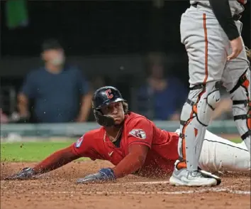  ?? Sue Ogrocki/Associated Press ?? Cleveland’s Bo Naylor, left, scores in the fifth inning Thursday night against Baltimore. The Guardians defeated the Orioles, 5-2, in Cleveland.