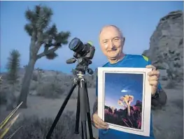  ??  ?? WALLY PACHOLKA has been photograph­ing the night skies over Joshua Tree for many years. Here he holds a shot he took of the Hale-Bopp comet in 1997.