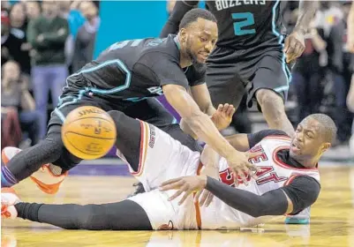  ?? NELL REDMOND/AP ?? Miami guard DwyaneWade, right, passes a loose ball from the floor as Charlotte Hornets guard KembaWalke­r reaches for
it.