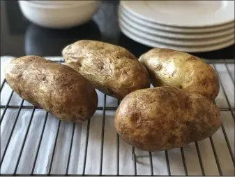  ?? ELIZABETH KARMEL — THE ASSOCIATED PRESS ?? Four baked potatoes rest on a rack in Amagansett, N.Y.
